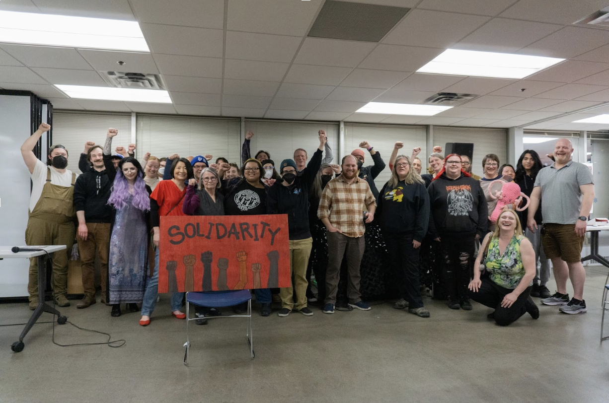 A crowd raises their fists in solidarity, at a fundraiser