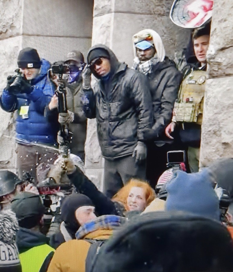 A redheaded woman sprays mace into a crowd of people
